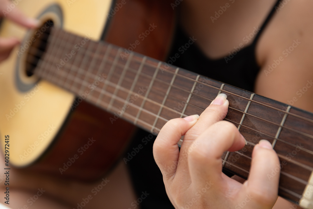 Close up of female hand playing guitar at home Close up of female hand playing guitar at home