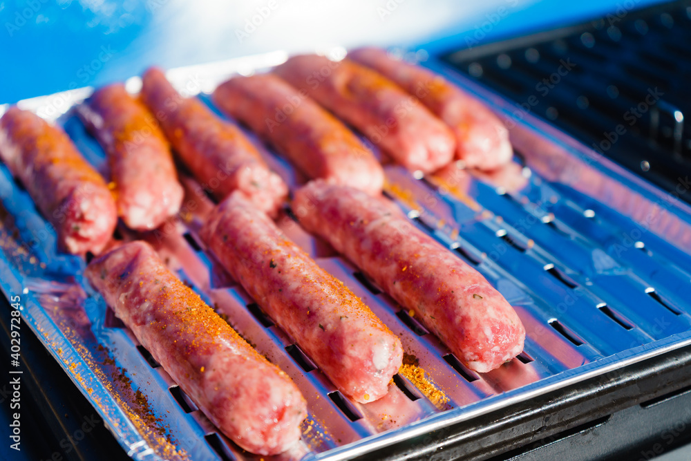 Sausages meat grilling on gas grill