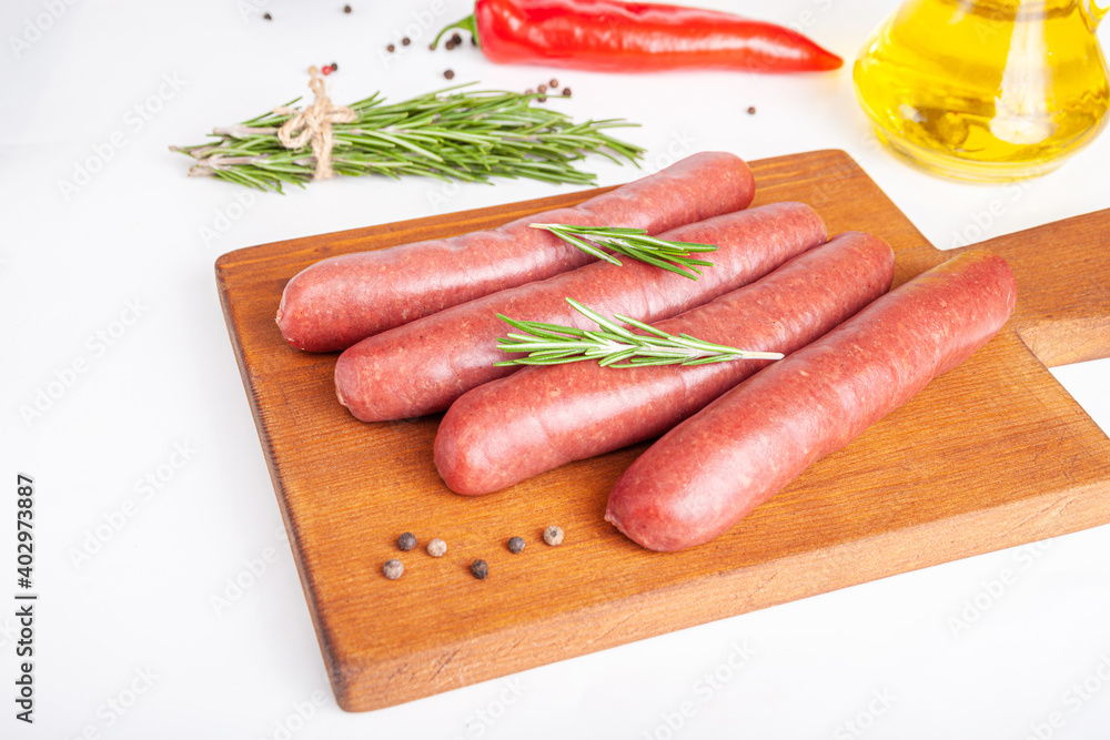 Raw meat beef sausages for grill and spicy, herbs rosemary, pepper, salt on table Raw meat beef sausages for grill and spicy, herbs rosemary, pepper, salt on table