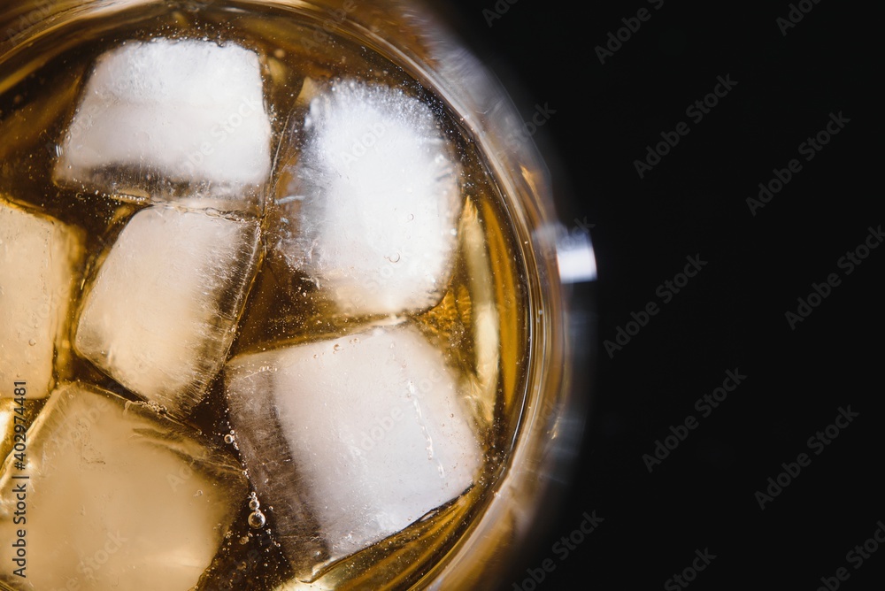Glass of scotch whiskey and ice over black background