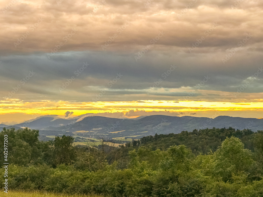 The landscape of the Beskydy Mountains from the viewpoint near Jicin during a colorful sunset and dark clouds in the sky and a view of the surrounding landscape. The landscape of the Beskydy Mountains from the viewpoint near Jicin during a colorful sunset and dark clouds in the sky and a view of the surrounding landscape.