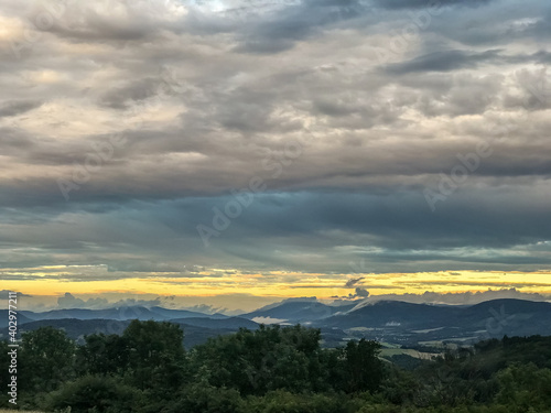 The landscape of the Beskydy Mountains from the viewpoint near Jicin during a rainy afternoon full of dark clouds in the sky and a view of the surrounding landscape.