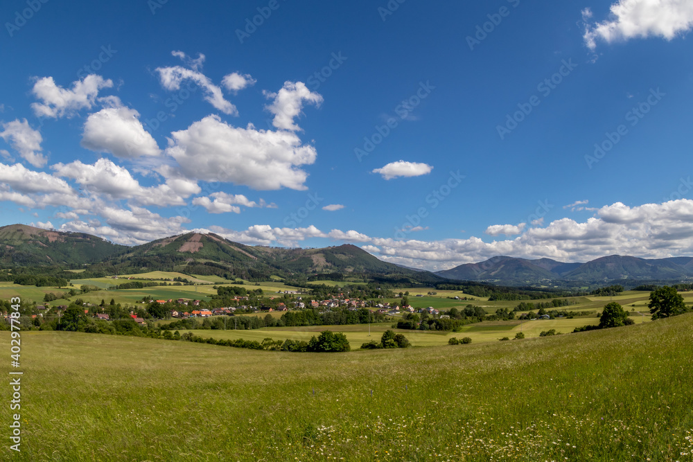 Ondrejnik and views of other Beskydy hills and mountains with white clouds and blue sky in the background during a sunny day. Ondrejnik and views of other Beskydy hills and mountains with white clouds and blue sky in the background during a sunny day.
