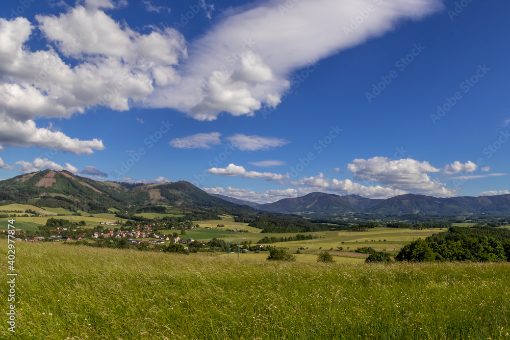 Ondrejnik and views of other Beskydy hills and mountains with white clouds and blue sky in the background during a sunny day. Ondrejnik and views of other Beskydy hills and mountains with white clouds and blue sky in the background during a sunny day.