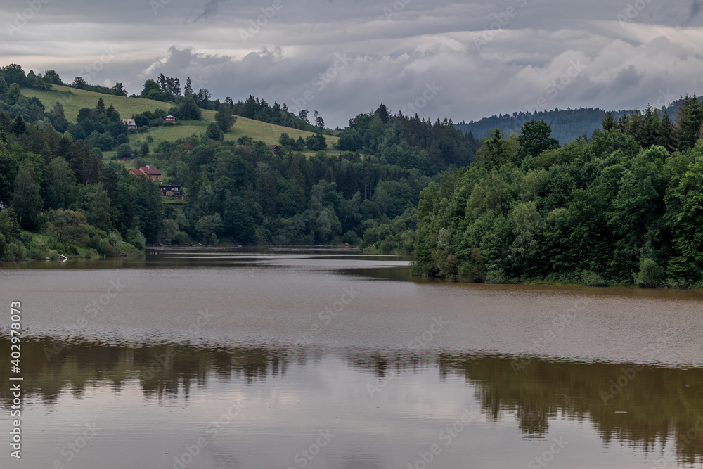 Water level of the Bystricka reservoir during a rainy afternoon with dark clouds in the sky.