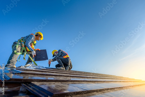 Two male workers wearing safety clothes Installing the roof tile house That is a ceramic tile roof On the construction site photo