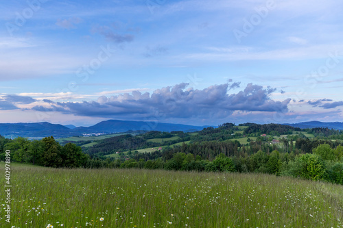 Landscape full of hills and mountains with clouds and blue sky with sun during colorful sunset Beskydy region. photo