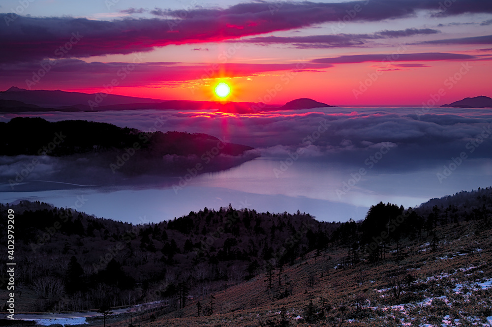 朝陽に照らされて赤く染まる空と雲。ドラマチックな夜明けの風景。日本の北海道、美幌峠で。