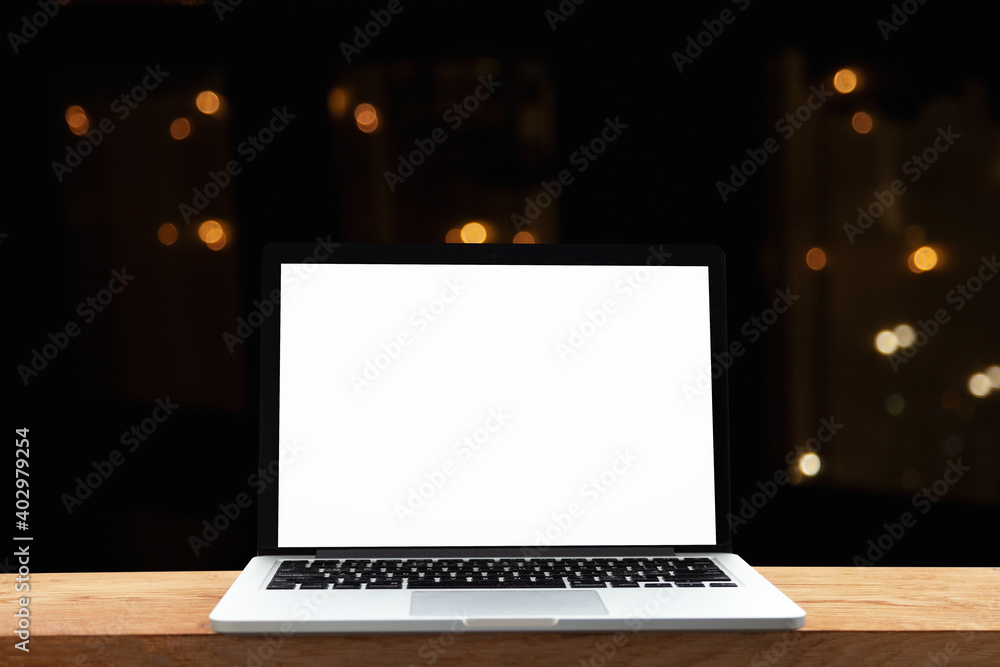 Notebook or laptop with blank screen on wooden table on blurred background in modern cafe restaurant bokeh light and light bulbs Notebook or laptop with blank screen on wooden table on blurred background in modern cafe restaurant bokeh light and light bulbs