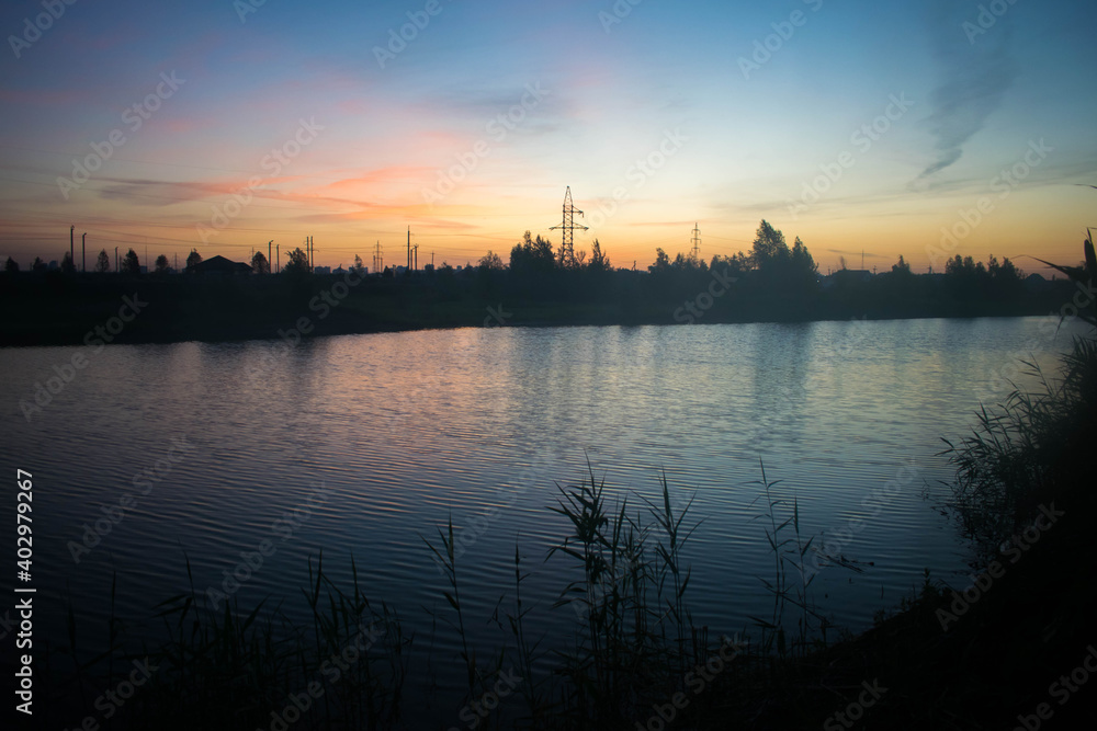 Lake. Sunset. Twilight landscape. Reflection in water. Reeds. Colorful sky.