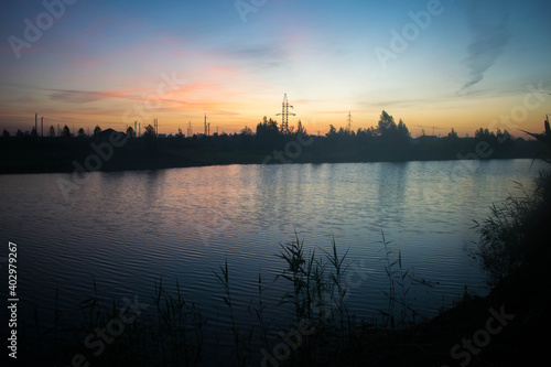 Lake. Sunset. Twilight landscape. Reflection in water. Reeds. Colorful sky.