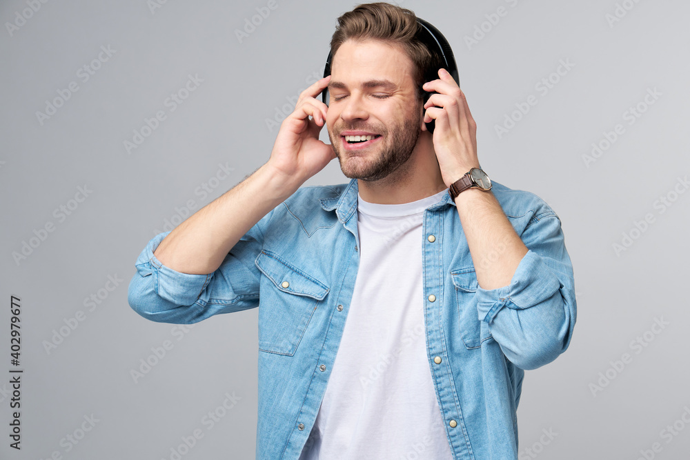 Close up portrait of cheerful young man enjoying listening to music wearing casual jeans outfit Close up portrait of cheerful young man enjoying listening to music wearing casual jeans outfit
