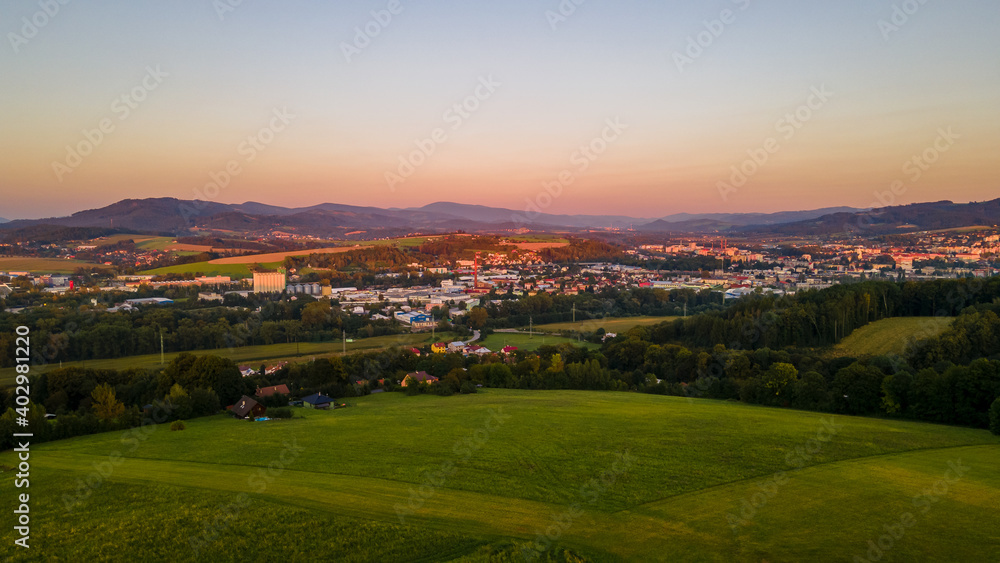 Aerial landscape view at orange sunset with field and village lying in the background.