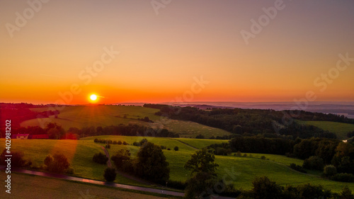 Aerial landscape view at orange sunset with field and village lying in the background.