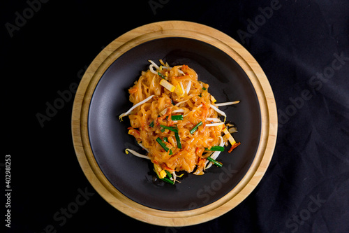 Udon noodles, pad thai, vegetarian vegetables on black plate, top view Asian Vegetarian Copy space