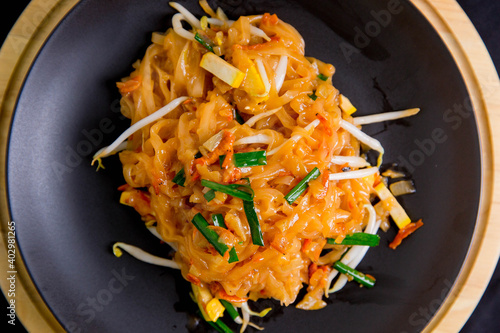 Udon noodles, pad thai, vegetarian vegetables on black plate, top view Asian Vegetarian Copy space