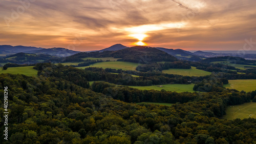 Aerial view of colorful clouds and mountainous hilly landscape at sunset over the horizon of Beskydy region.