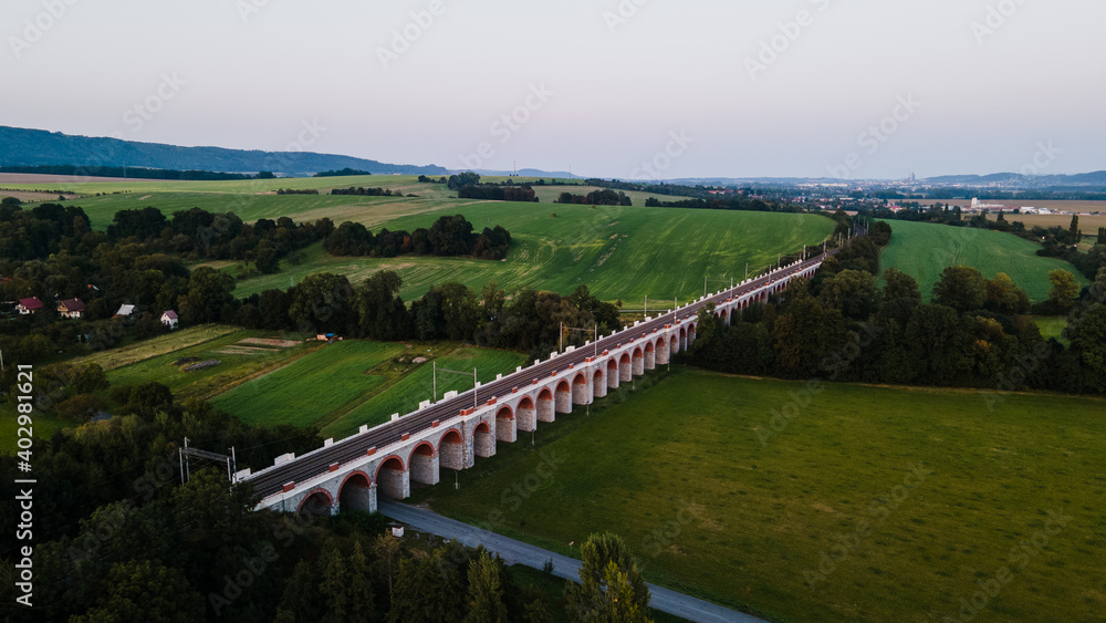 Aerial view of the railway viaduct near Lipnik nad Becvou with the surrounding countryside and the village lying nearby during the late afternoon.