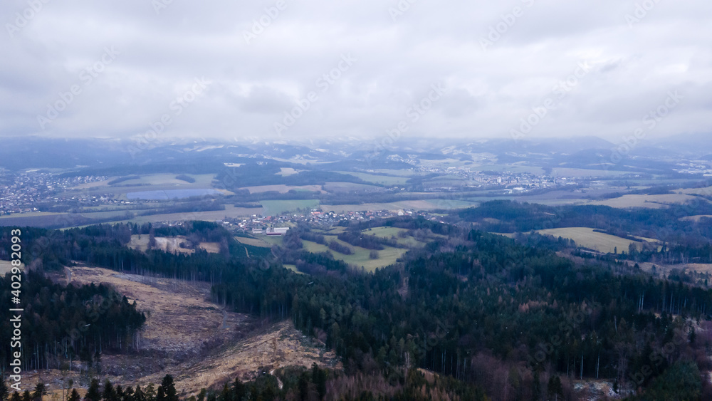 Aerial view of a hilly landscape with freshly fallen snow during a light snowfall in the Beskydy region.