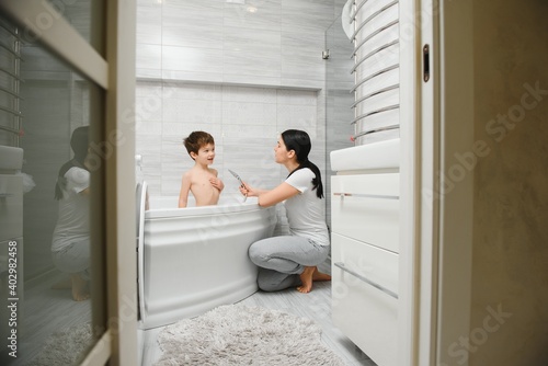 Mother washing little son in bathroom