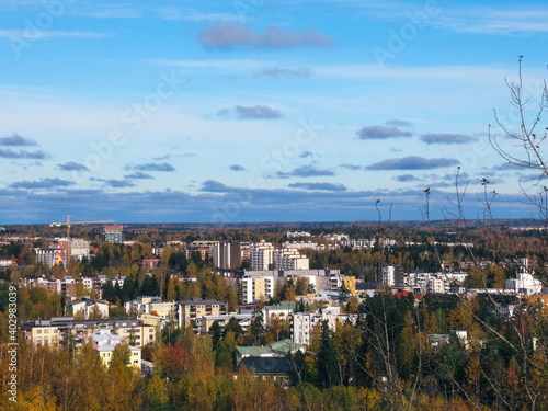 City panorama with apartment buildings, trees in autumn colors and blue sky with some clouds. © Jarmo
