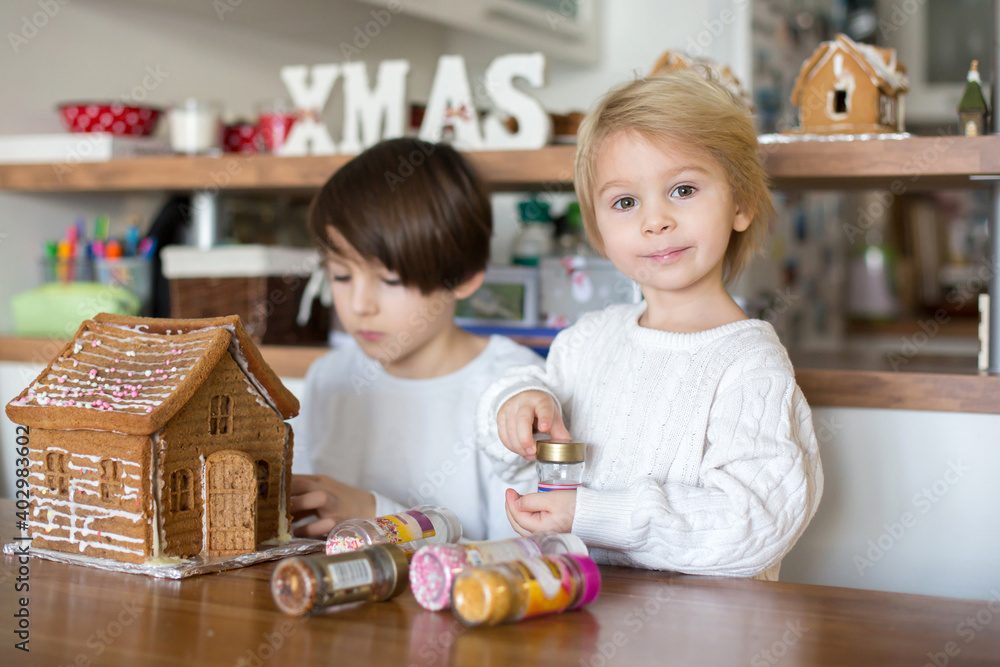 Children, boys, decorating home made ginger bread house at home Children, boys, decorating home made ginger bread house at home