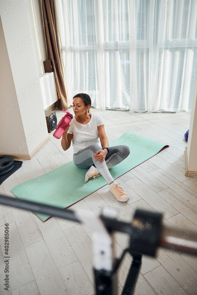 Fototapeta premium Tired athletic lady replenishing the water balance