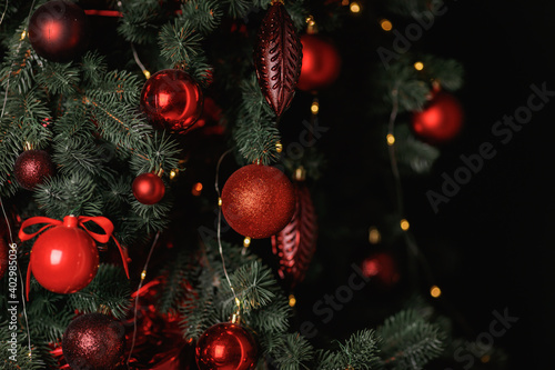 Red balls decorate a Christmas tree on a green background. Selective focus.