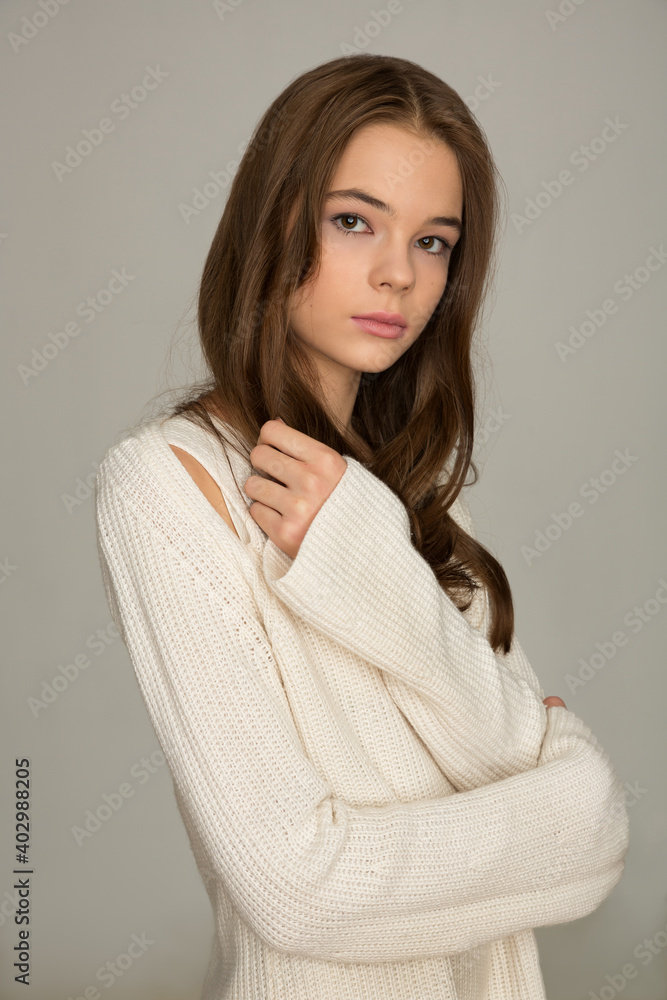 beautiful girl teenager with in a stylish knitted white dress posing in the studio on a white background beautiful girl teenager with in a stylish knitted white dress posing in the studio on a white background