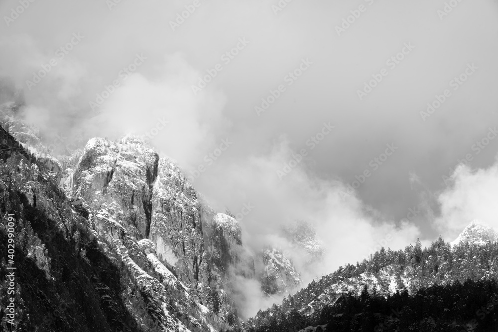 le nuvole sulla montagna in inverno, la luce che filtra le nuvole attorno una montagna innevata, lo splendido panorama invernale sulle dolomiti