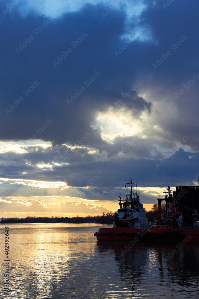 Fragment of the ship near the pier against of a colorful sunset over Danube river