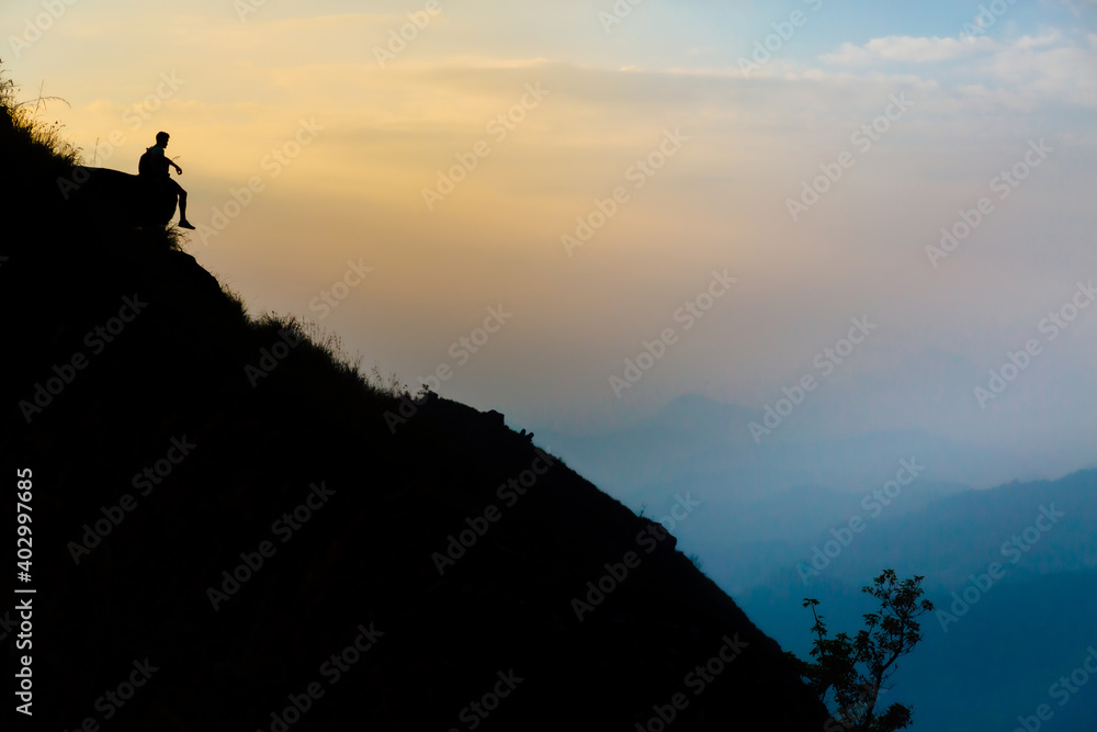 Mountaineer watching the sunrise sitting on a rock
