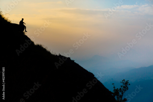 Mountaineer watching the sunrise sitting on a rock