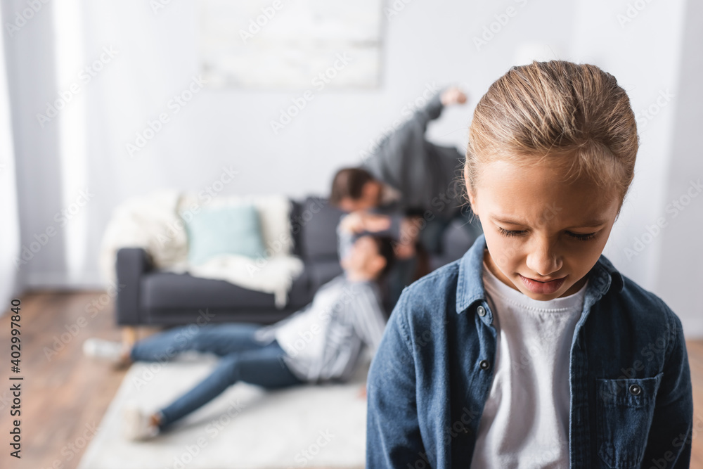 girl standing near father beating mother on floor in living room on blurred background girl standing near father beating mother on floor in living room on blurred background