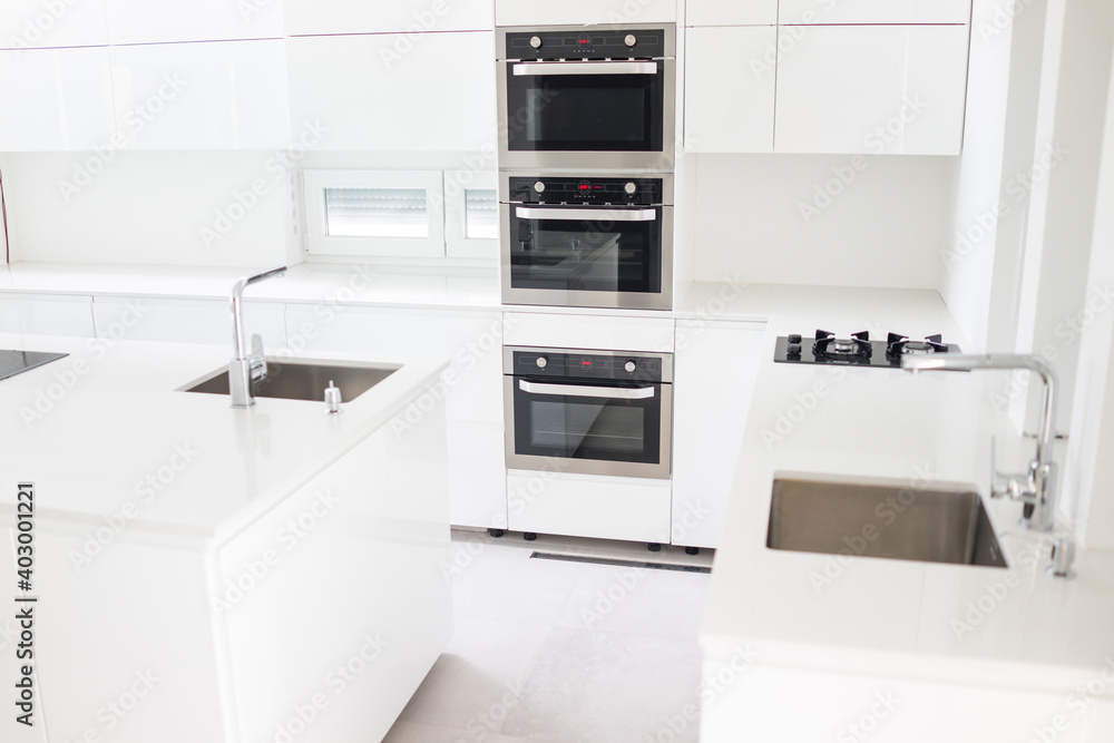 White organised kitchen with modern elements in an apartment . High quality photo White organised kitchen with modern elements in an apartment . High quality photo