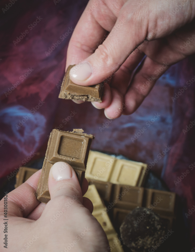 Fototapeta premium The female hands holding a handmade chocolate.Confectionery on a dark background.