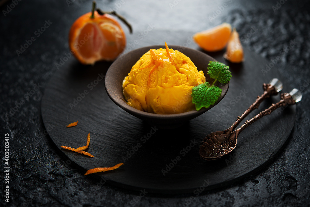 Tangerine ice cream in a cup, sorbet on a black background - obrazy, fototapety, plakaty 