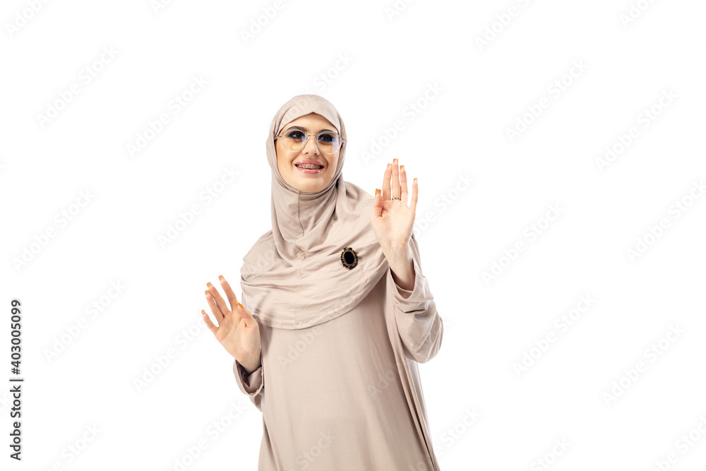 Showing. Beautiful arab woman posing in stylish hijab isolated on studio background with copyspace for ad. Fashion, beauty, style concept. Female model with trendy make up, manicure and accessories. Showing. Beautiful arab woman posing in stylish hijab isolated on studio background with copyspace for ad. Fashion, beauty, style concept. Female model with trendy make up, manicure and accessories.