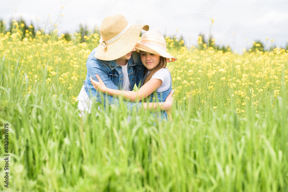 outdoor walk. summer in field. yellow flowers, road.Mom hugs her daughter, regrets and protects. upbringing and care. on nature,summer day vacation. playing at sunset time. friendly family. outdoor walk. summer in field. yellow flowers, road.Mom hugs her daughter, regrets and protects. upbringing and care. on nature,summer day vacation. playing at sunset time. friendly family.