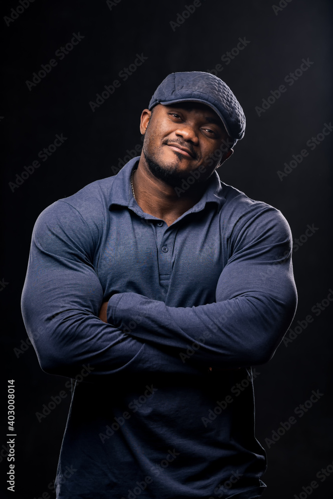 African american bodybuilder stands crosshands on black studio background.