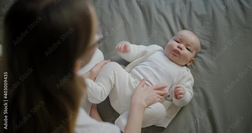 Beautiful mother with her baby. Young beautiful woman looks at her little daughter. Baby girl laughing in her mother's arms. Beautiful mother with her baby. Young beautiful woman looks at her little daughter. Baby girl laughing in her mother's arms.