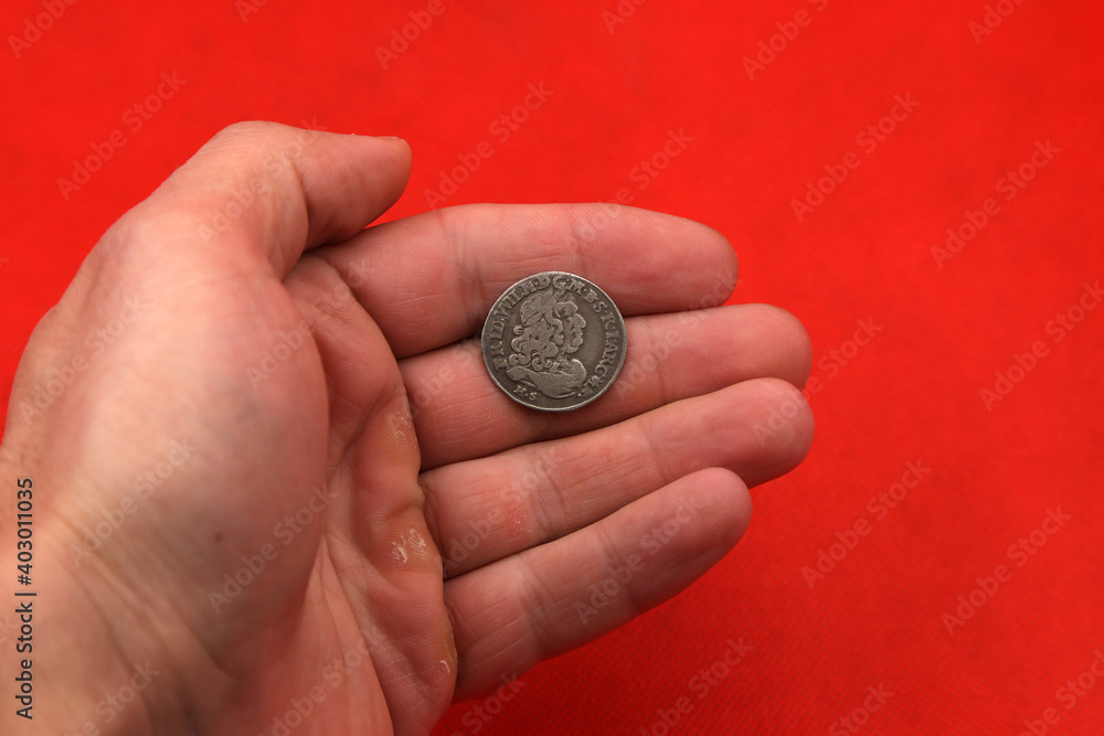 Medieval european silver coin in hand on red background Medieval european silver coin in hand on red background