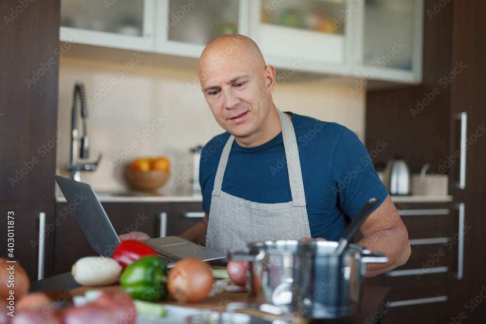 A young man searches the internet for a recipe. House, kitchen. A young man searches the internet for a recipe. House, kitchen.