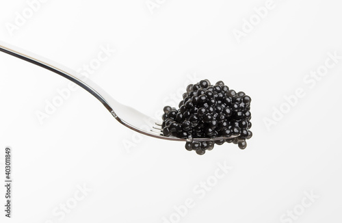 fresh grainy black paddlefish caviar in metal fork on white background