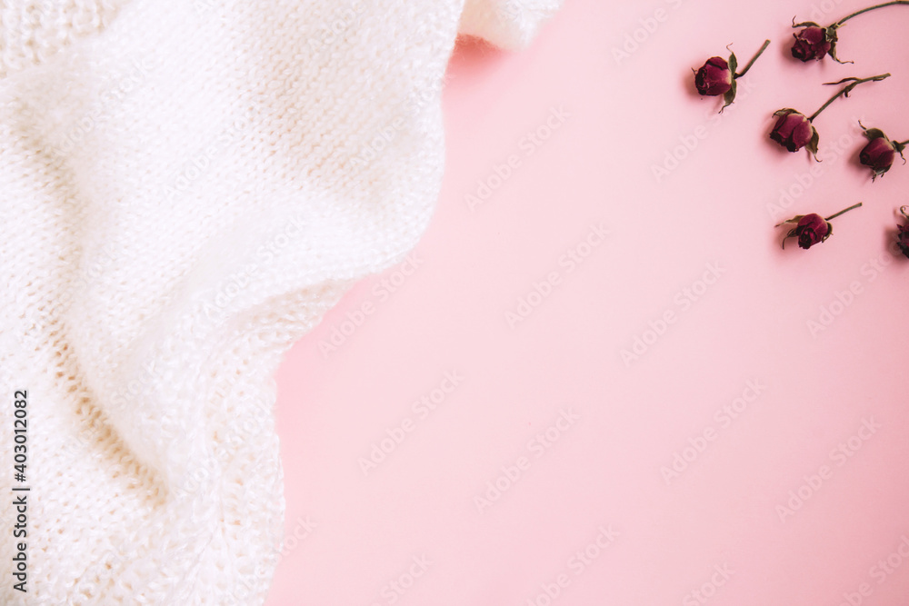 Valentine's Day background. Miniature red rose buds and white knitted fabric on pastel pink background. Valentines day concept. Flat lay with copy space Valentine's Day background. Miniature red rose buds and white knitted fabric on pastel pink background. Valentines day concept. Flat lay with copy space
