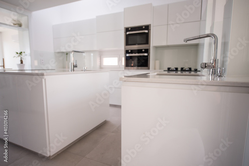 White organised kitchen with modern elements in an apartment . High quality photo