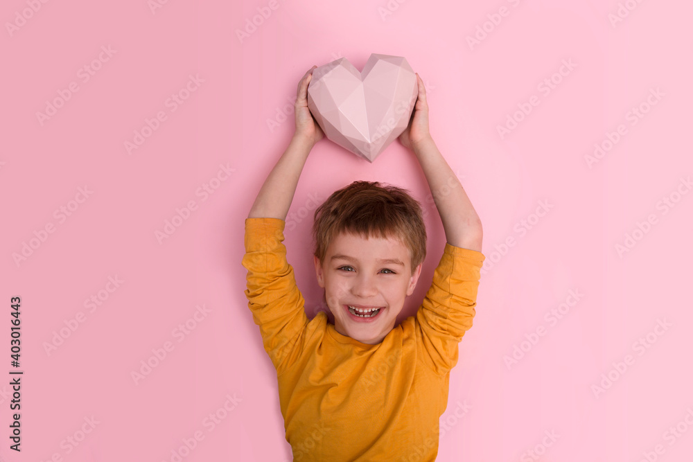 Happy kid boy hold a heart against a pink background. St. Valentine's comcept. banner. Copy space. Mom's Day Happy kid boy hold a heart against a pink background. St. Valentine's comcept. banner. Copy space. Mom's Day
