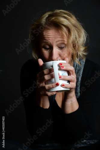 FRAU TRINKT  aus tasse heißgetränk lowkey schatten dunkel hintergrund kaffeee cappucion glühwein kalt, winter photo