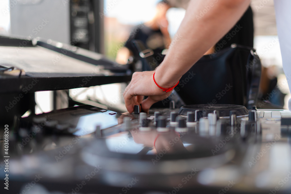 DJ playing music at outdoor event. Person operating mixer at music festival. Close up shot of deejay mixing at the party