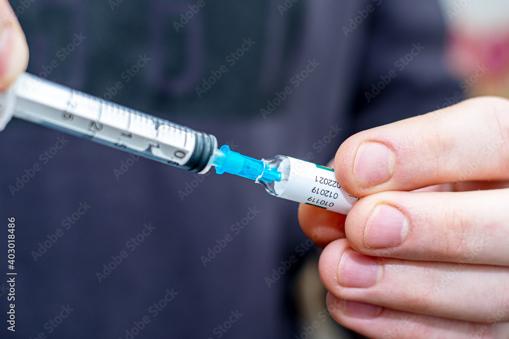 the doctor takes the vaccine with a syringe from an ampoule the doctor takes the vaccine with a syringe from an ampoule